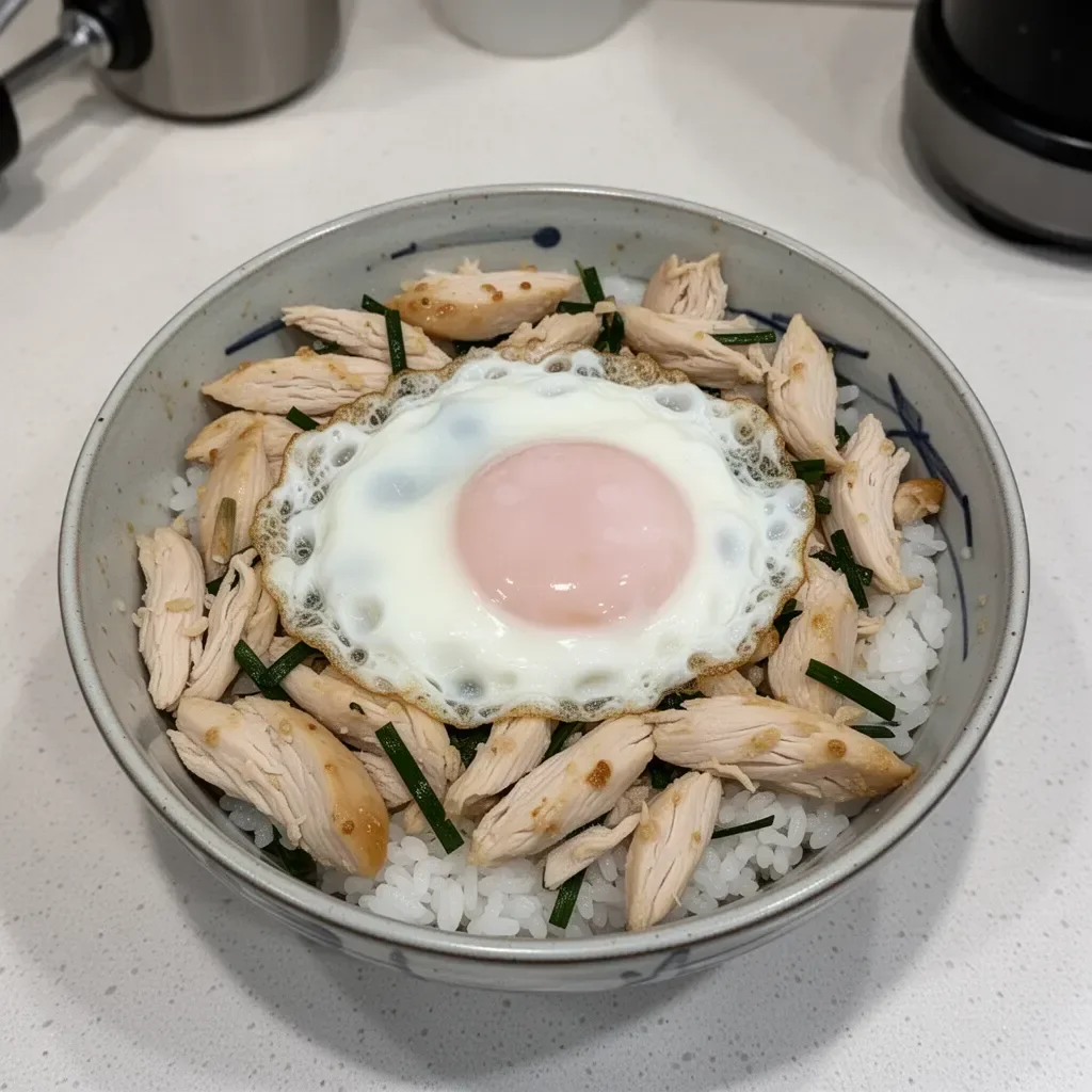 Japanese inspired chicken and egg rice bowl served with rice and garnishments.
