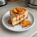 Slice of delicious peach cheesecake topped with fresh peach slices.